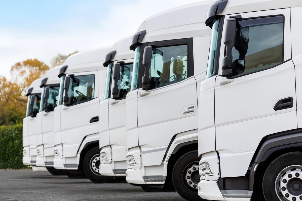 A fleet of modern commercial delivery vehicles parked in a line at a logistics depot